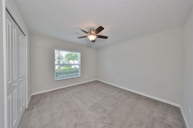 unfurnished bedroom with light carpet, a textured ceiling, ceiling fan, and a closet