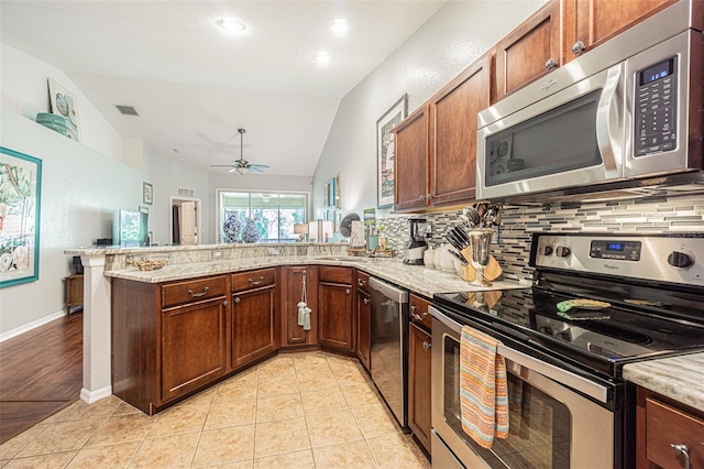 kitchen with kitchen peninsula, light tile patterned floors, stainless steel appliances, and lofted ceiling