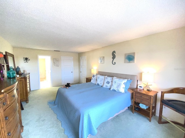 bedroom with light carpet, a textured ceiling, and connected bathroom