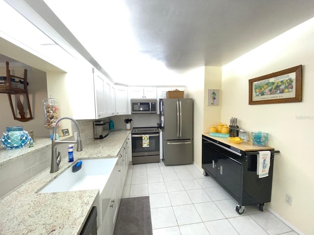 kitchen featuring appliances with stainless steel finishes, tasteful backsplash, light stone counters, sink, and white cabinets