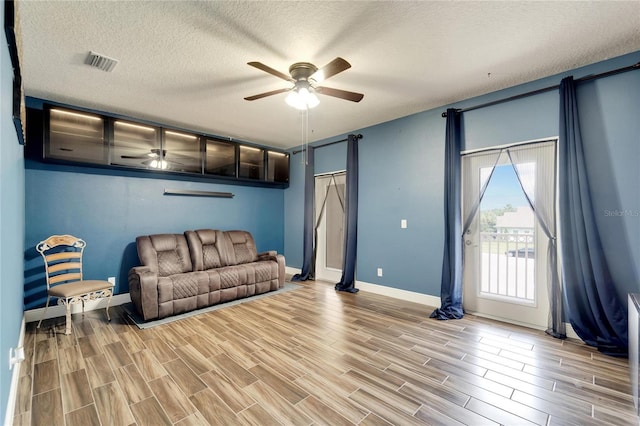 19300 Lonesome Pine Dr, Land O Lakes, FL 34638 - living room featuring a ceiling fan, wood tiled floor, visible vents, and a textured ceiling