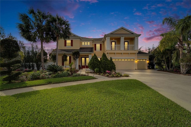 view of front of house featuring stucco siding, concrete driveway, an attached garage, a front yard, and a balcony