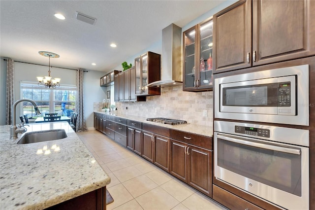 19300 Lonesome Pine Dr, Land O Lakes, FL 34638 - kitchen featuring stainless steel appliances, a sink, visible vents, wall chimney range hood, and tasteful backsplash
