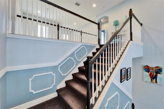 19300 Lonesome Pine Dr, Land O Lakes, FL 34638 - staircase featuring arched walkways, recessed lighting, visible vents, a towering ceiling, and baseboards
