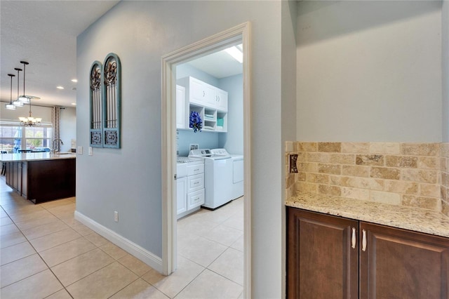 19300 Lonesome Pine Dr, Land O Lakes, FL 34638 - hall featuring light tile patterned flooring, independent washer and dryer, baseboards, and an inviting chandelier