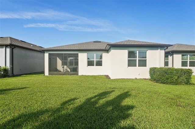 back of property featuring a lawn and a sunroom