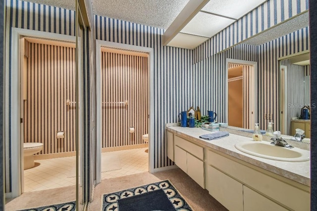 bathroom with tile patterned floors, vanity, a textured ceiling, and toilet