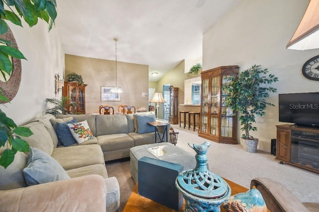 living room with a notable chandelier, carpet floors, and high vaulted ceiling