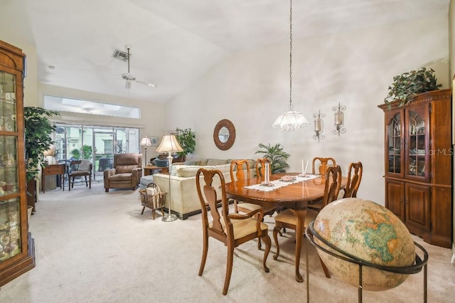 carpeted dining space with ceiling fan and high vaulted ceiling