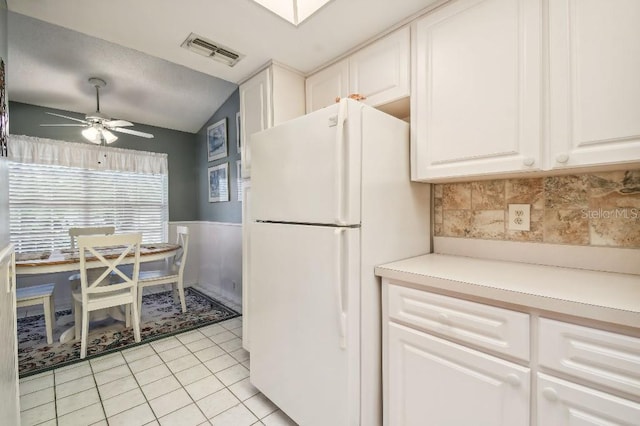 kitchen with white cabinetry, light tile patterned floors, vaulted ceiling, ceiling fan, and white refrigerator