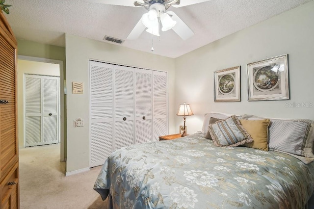 bedroom featuring a closet, a textured ceiling, ceiling fan, and light colored carpet