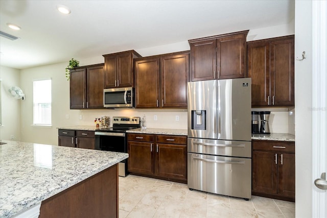 kitchen featuring appliances with stainless steel finishes, light stone countertops, and light tile patterned floors