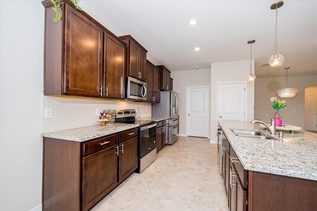 kitchen with stainless steel appliances, sink, pendant lighting, backsplash, and light tile patterned floors