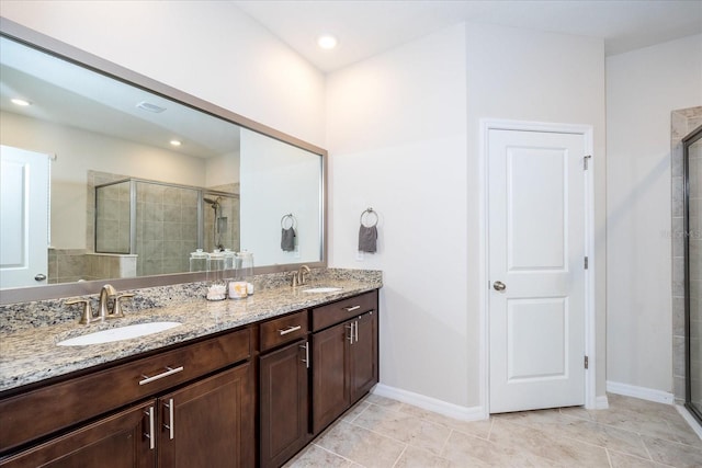 bathroom with a shower with shower door, double sink vanity, and tile patterned flooring