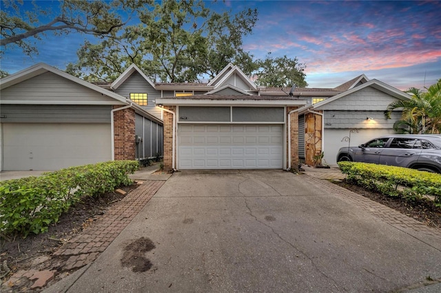 view of front of property featuring a garage, concrete driveway, and brick siding