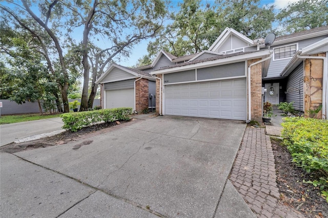 view of front of property featuring an attached garage, concrete driveway, and brick siding