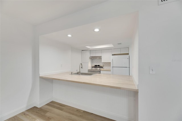 kitchen with backsplash, stainless steel range with electric cooktop, white cabinets, sink, and white fridge