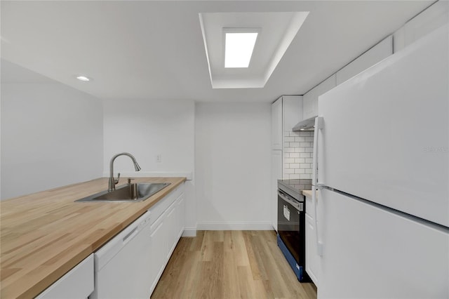 kitchen with white appliances, exhaust hood, sink, decorative backsplash, and white cabinetry