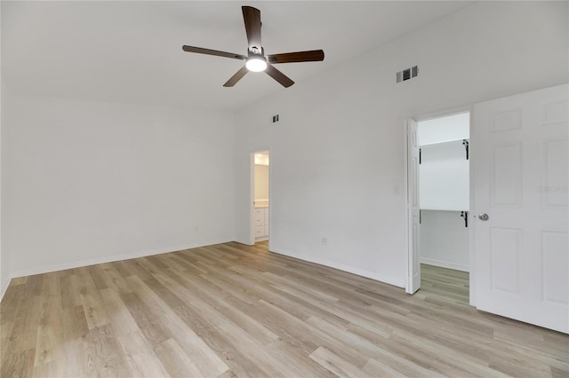 unfurnished bedroom with light wood-style floors, a walk in closet, visible vents, and baseboards