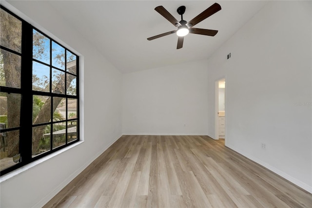 spare room featuring lofted ceiling, light wood-style flooring, a ceiling fan, visible vents, and baseboards