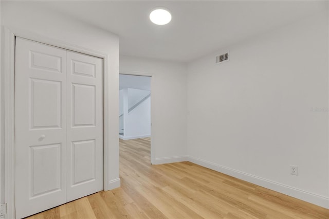 spare room featuring baseboards, visible vents, and light wood-style floors