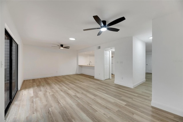 unfurnished living room with visible vents, light wood-style floors, a sink, ceiling fan, and baseboards