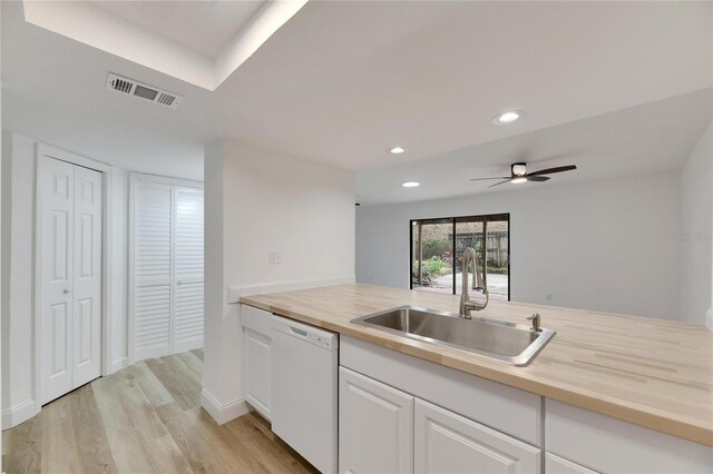 kitchen with white dishwasher, a sink, visible vents, white cabinetry, and light wood finished floors