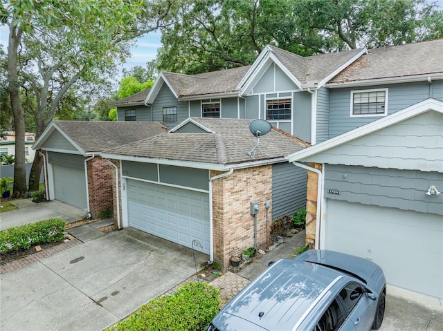 view of front of home with a shingled roof, brick siding, driveway, and a garage