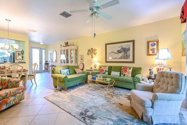 tiled living room with ceiling fan with notable chandelier