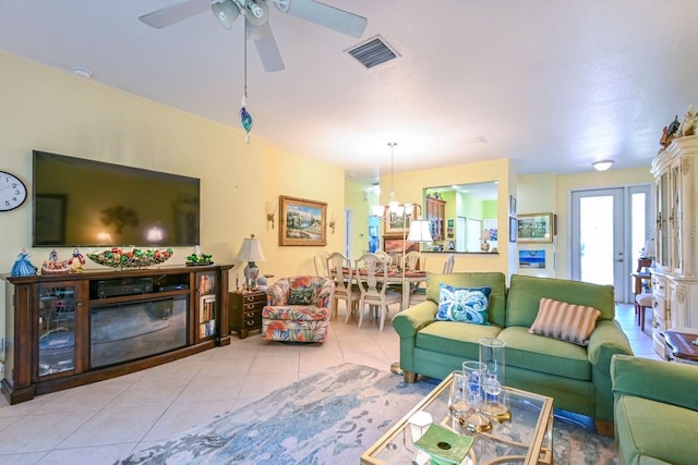 tiled living room featuring ceiling fan with notable chandelier