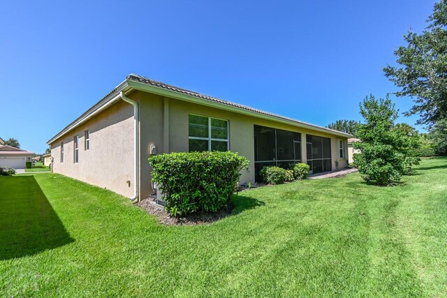 view of side of property featuring a sunroom and a yard