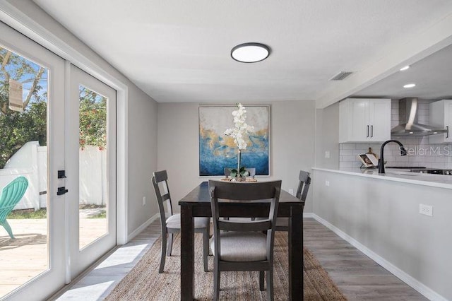 dining area featuring french doors, sink, and light wood-type flooring