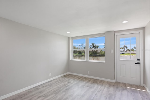 entrance foyer featuring a water view, plenty of natural light, and light wood-type flooring