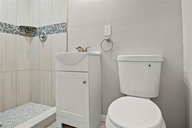 bathroom featuring vanity, a tile shower, and toilet