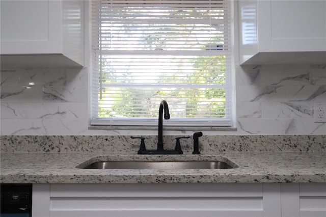 room details with light stone countertops, tasteful backsplash, white cabinetry, and sink