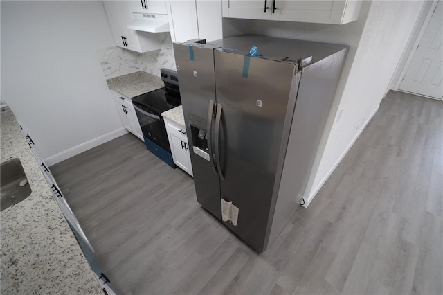 kitchen featuring light stone counters, white cabinetry, stainless steel refrigerator with ice dispenser, and black electric range