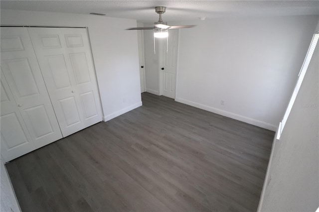 unfurnished bedroom featuring dark hardwood / wood-style flooring, ceiling fan, a closet, and a textured ceiling