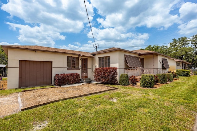 single story home with an attached garage, driveway, a front yard, and stucco siding