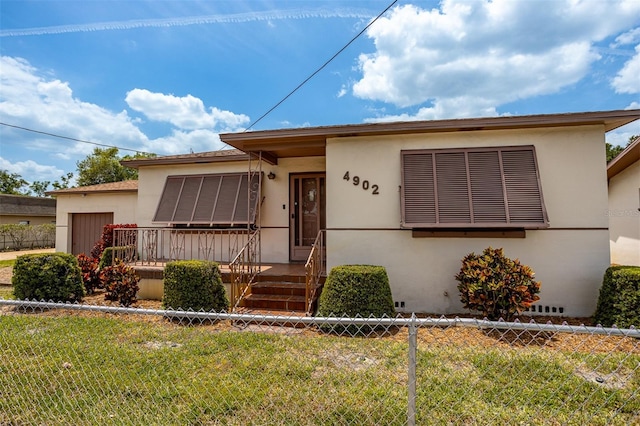 view of front of home with a garage, a front yard, fence, and stucco siding