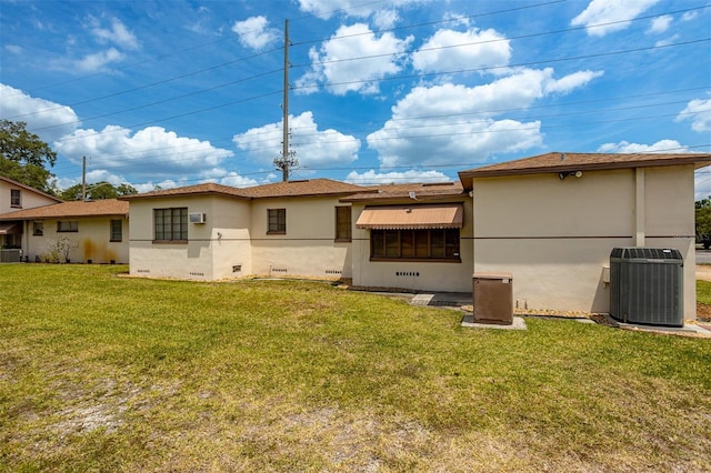 rear view of property with stucco siding, a lawn, and central air condition unit