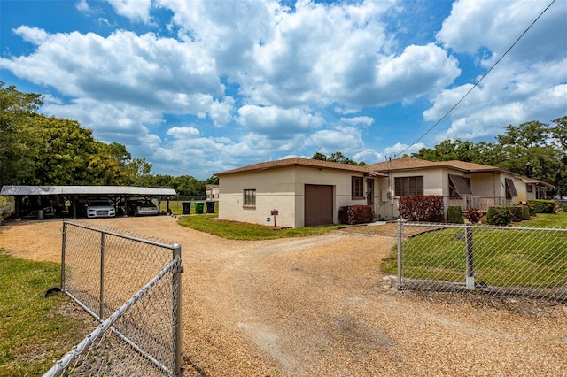 view of front of home with fence, driveway, stucco siding, a carport, and a front lawn