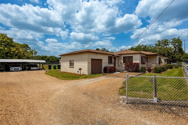 view of front of property featuring dirt driveway, a front lawn, fence, and stucco siding