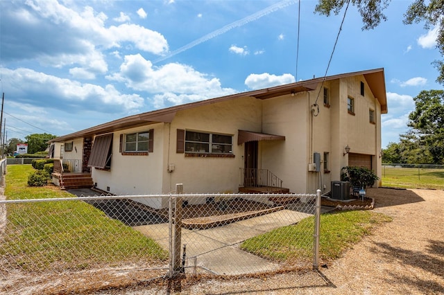 view of front facade featuring central AC unit, a front yard, fence, and stucco siding