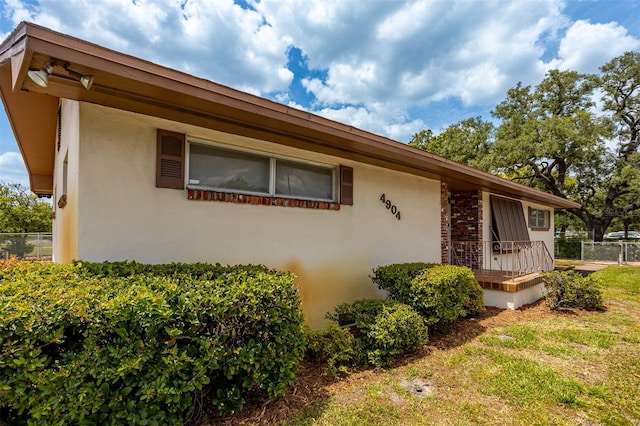 view of home's exterior featuring stucco siding, fence, and brick siding