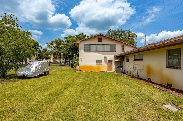 rear view of property with crawl space, central AC, a lawn, and stucco siding