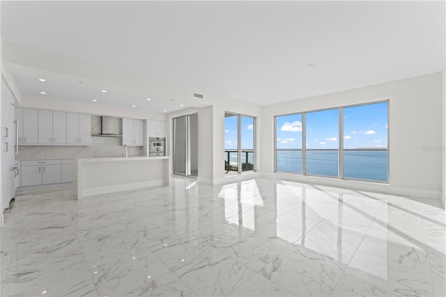 unfurnished living room with plenty of natural light and a water view