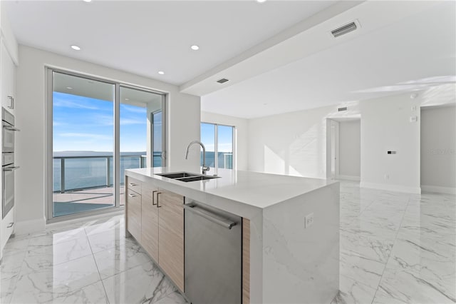 kitchen with a center island with sink, stainless steel dishwasher, a water view, and sink