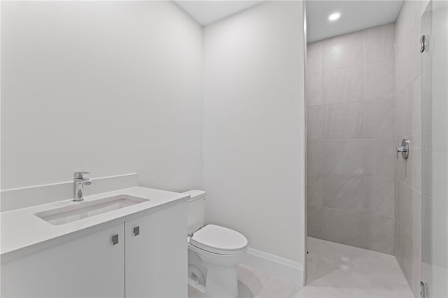 bathroom featuring a tile shower, tile patterned flooring, vanity, and toilet