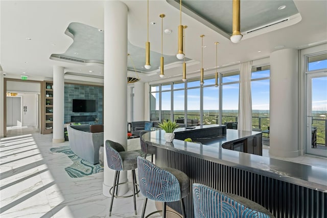 interior space with decorative light fixtures, a breakfast bar area, and a tray ceiling