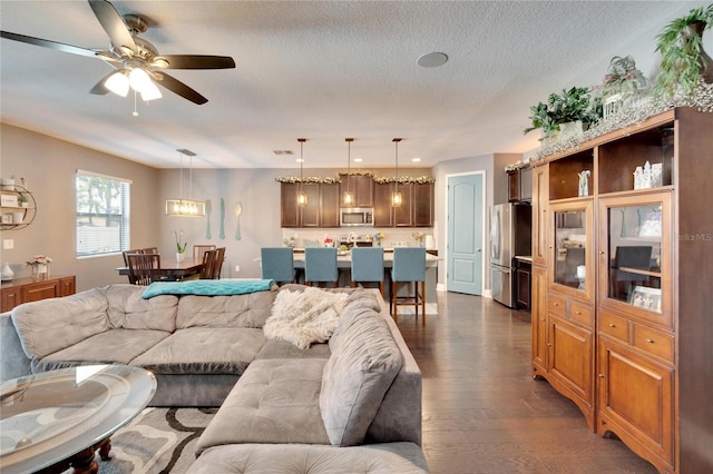 living room with ceiling fan, dark hardwood / wood-style floors, and a textured ceiling